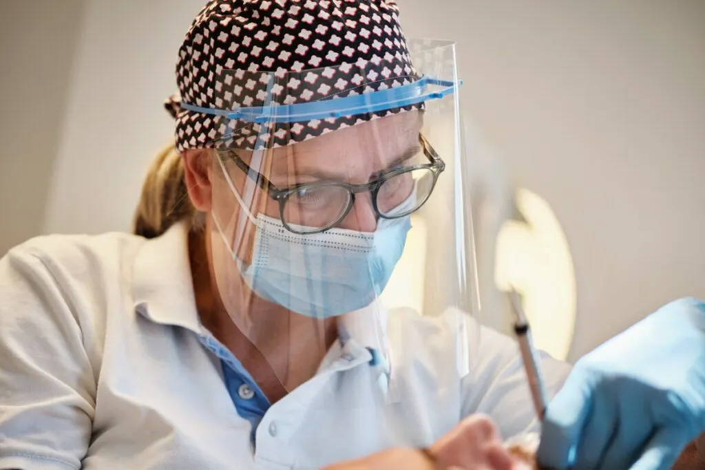 Tandarts met spatbril aan het werk in de behandelkamer